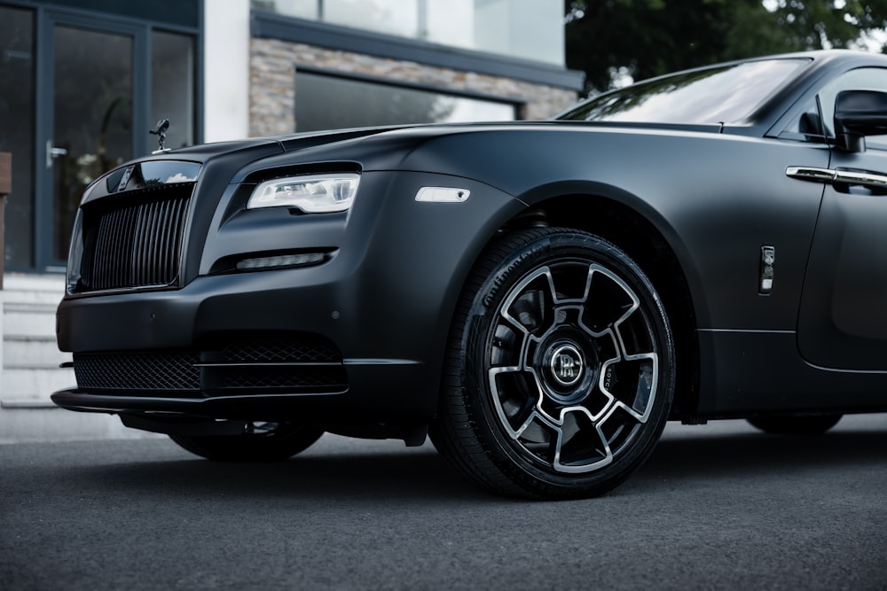 a black rolls royce parked in front of a building