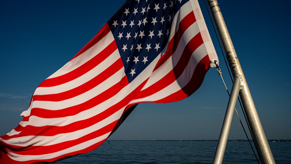 a large american flag flying over a body of water