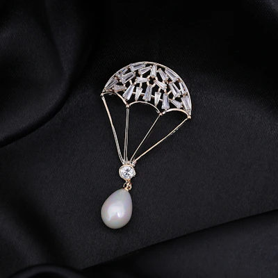 a brooch with a pearl hanging from it