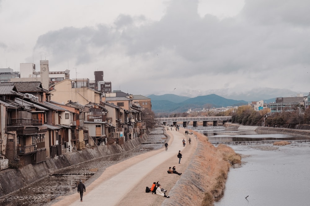 a group of people walking down a street next to a river