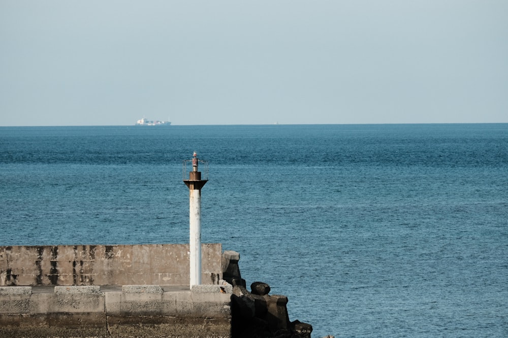 Ein Leuchtturm auf einem Pier neben dem Meer