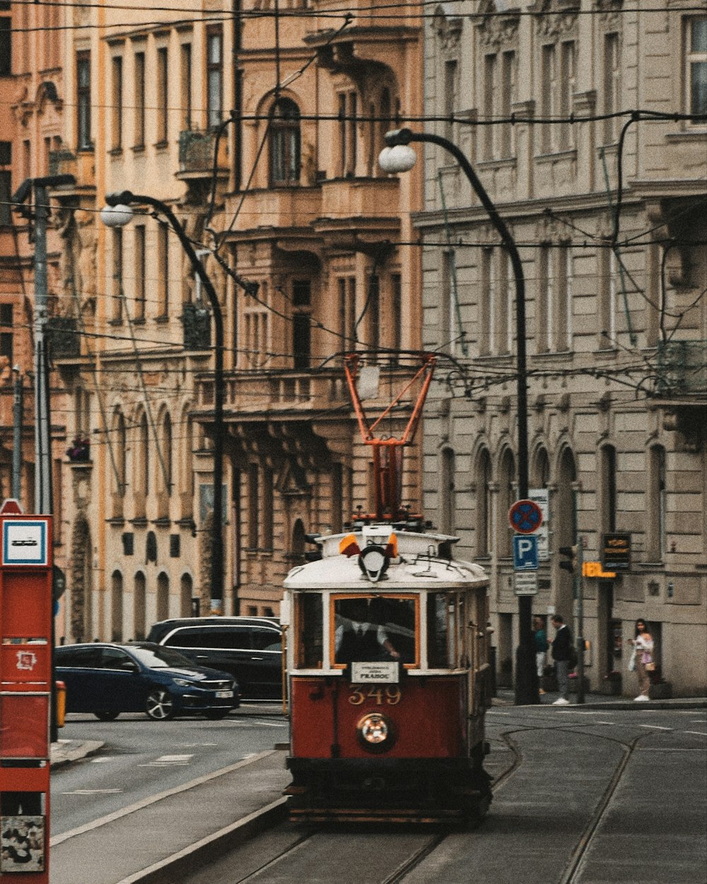 a red trolley car traveling down a street next to tall buildings