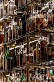 A collection of assorted liquor bottles displayed on glass shelves, arranged in a well-lit setting with a variety of shapes, sizes, and labels on the bottles. The shelves are crafted from reflective materials, enhancing the scarcity and selection of the spirits.