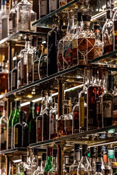 Various spirits and liquors arranged neatly on backlit shelves