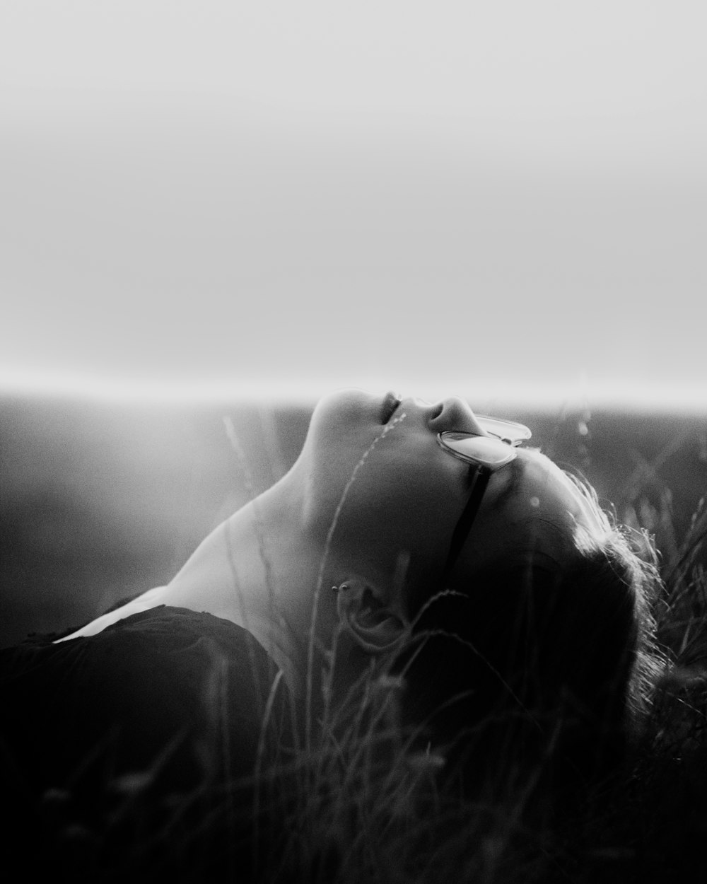a black and white photo of a woman laying in the grass