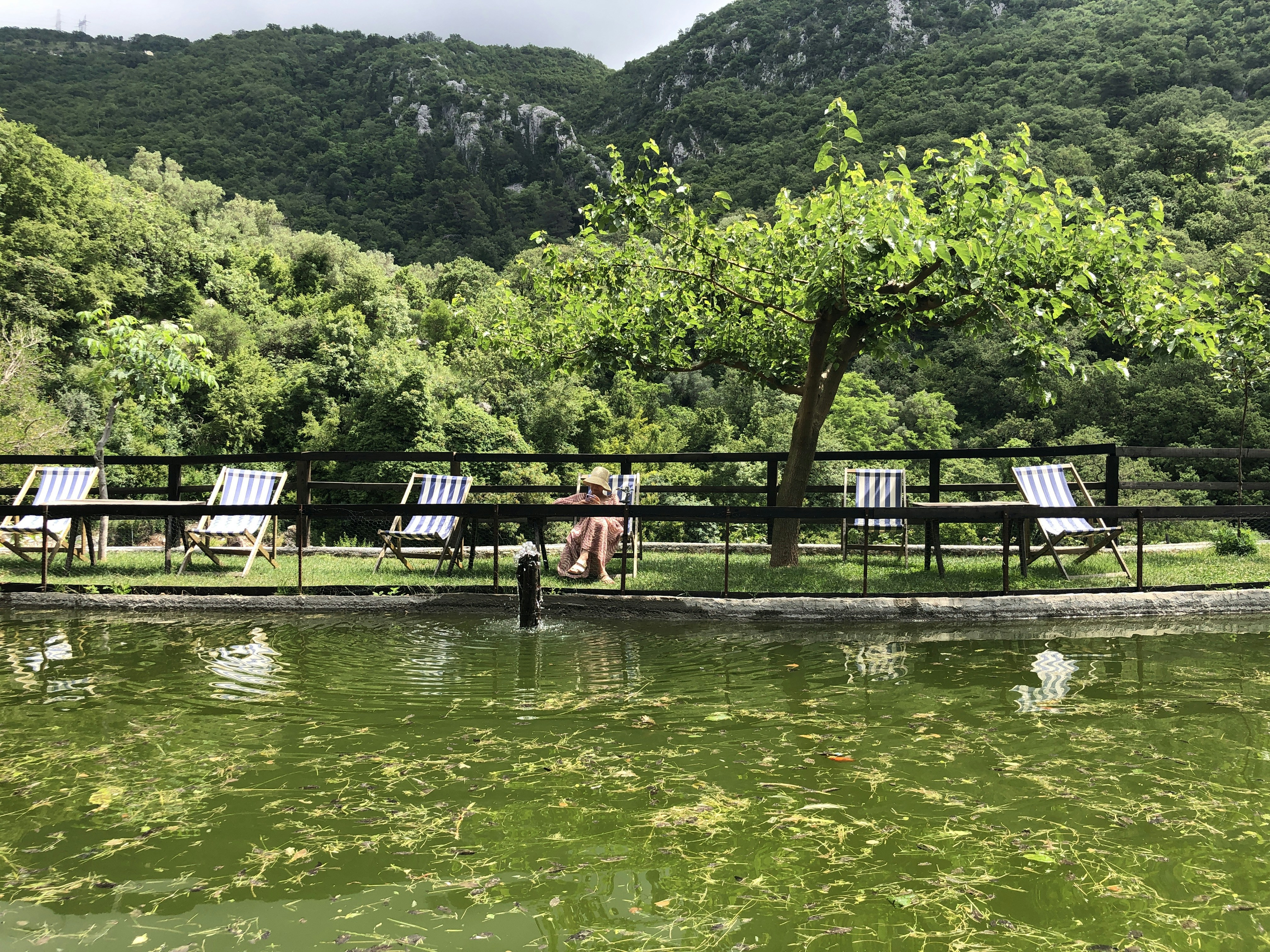 a man sitting on a bench next to a body of water