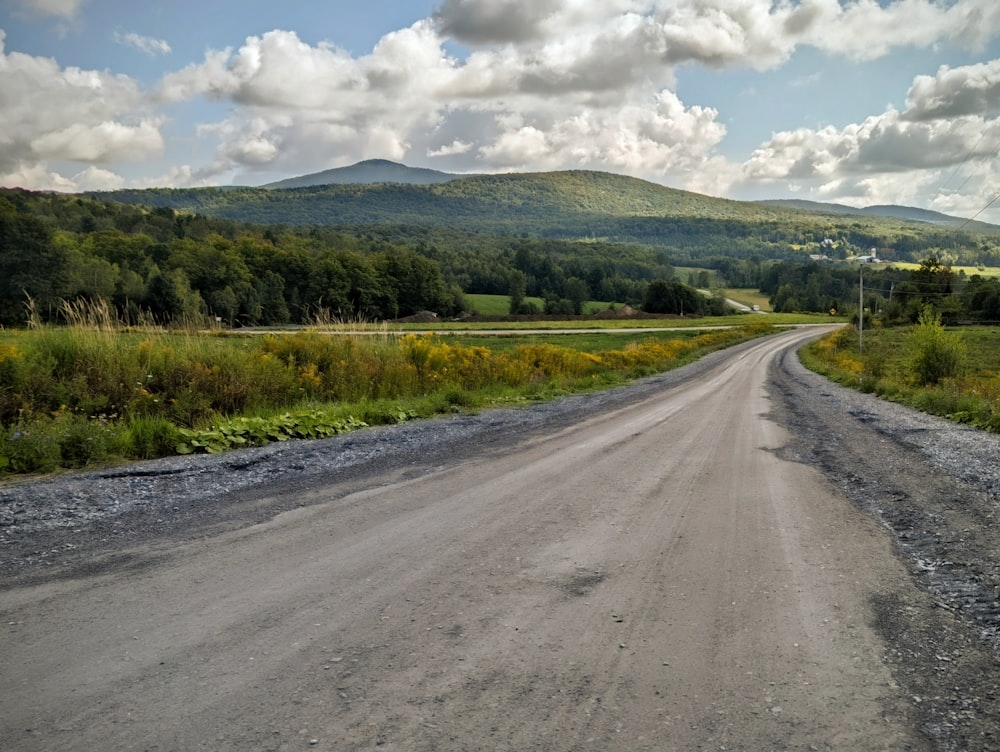 a dirt road with a mountain in the background