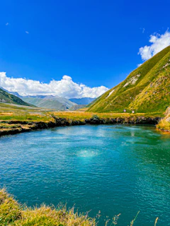 A serene landscape featuring a winding river surrounded by lush green hills under a clear blue sky.