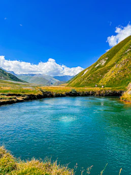 A serene landscape featuring a winding river surrounded by lush green hills under a clear blue sky.