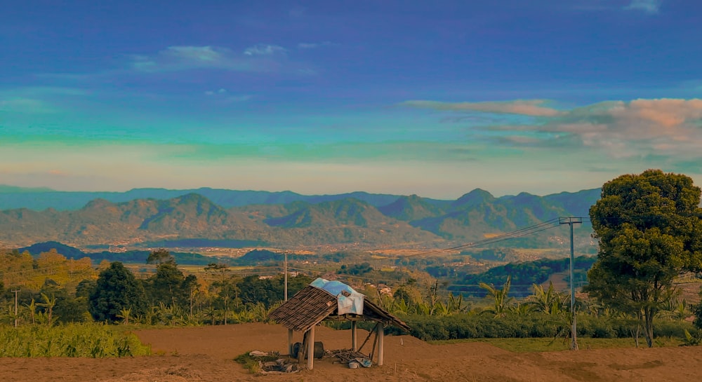 uma cabana em um campo com montanhas ao fundo