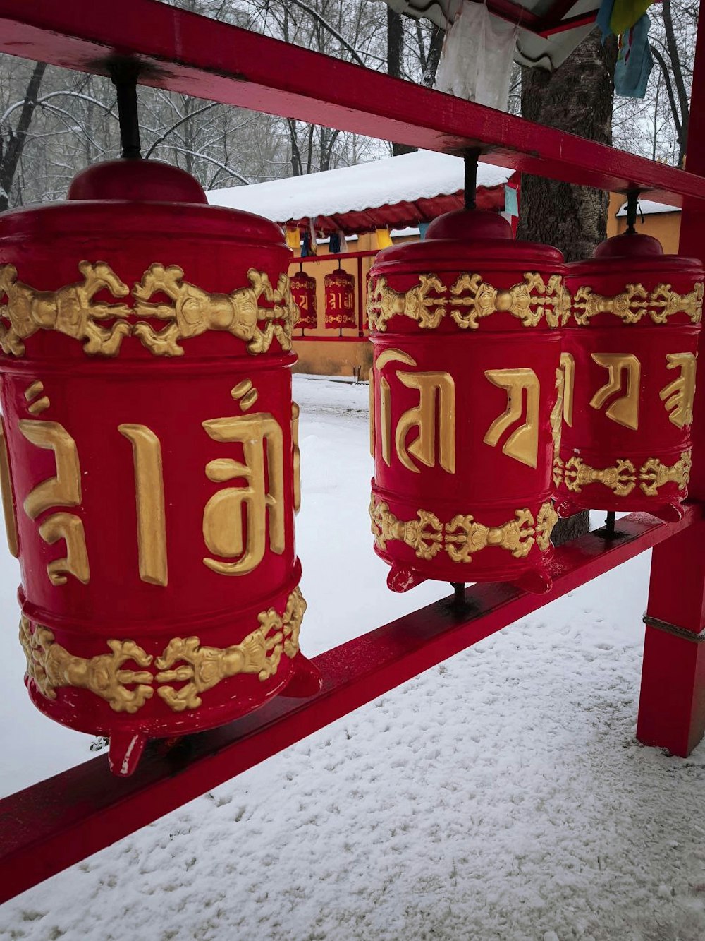 a row of red bells sitting on top of a snow covered ground