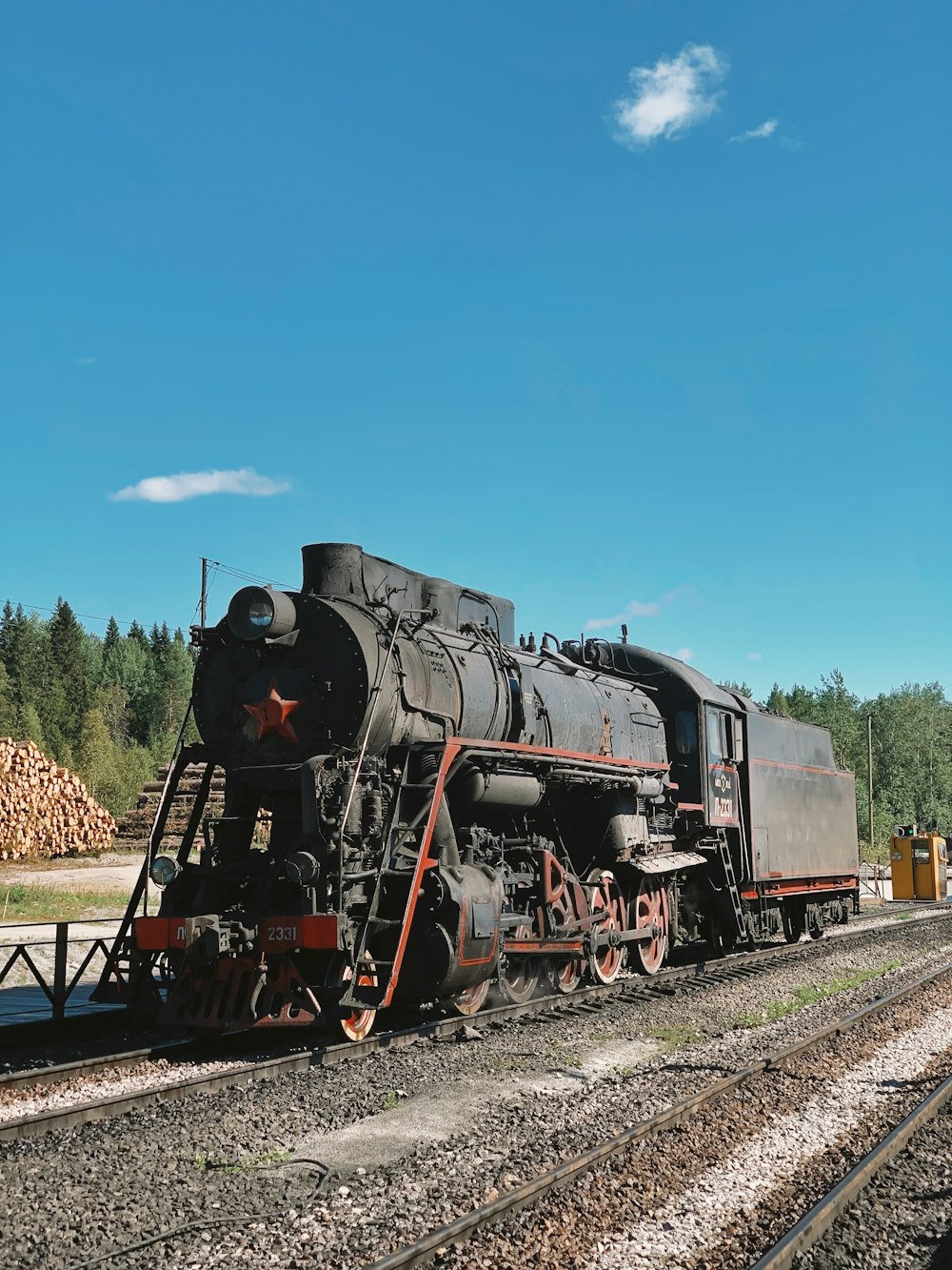 a black train traveling down train tracks next to a forest