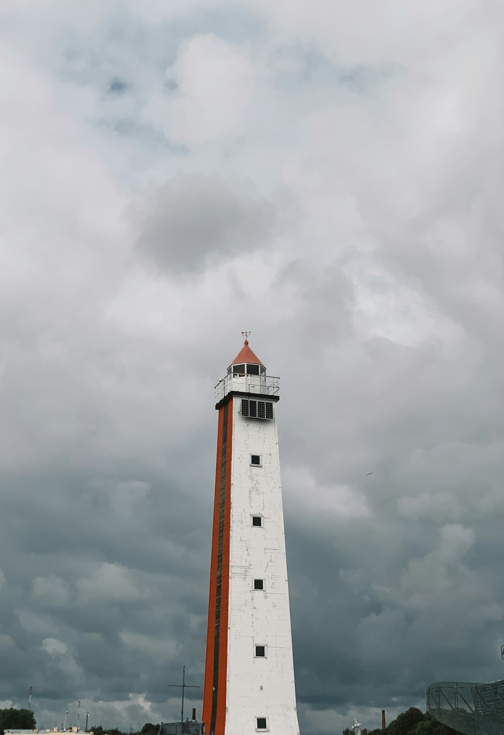 a white and red lighthouse on a cloudy day