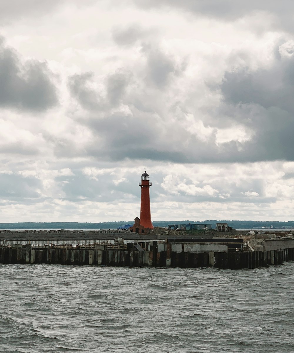 a red light house sitting on top of a pier