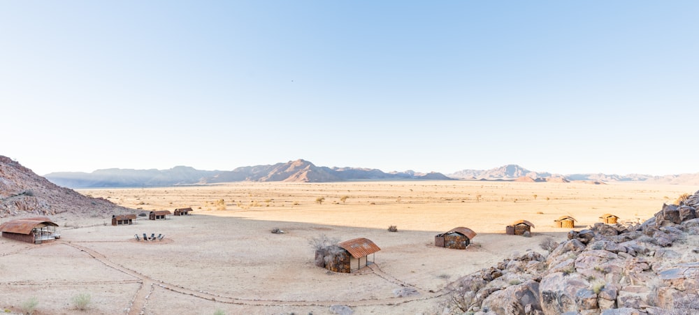 Un groupe de huttes dans un désert avec des montagnes en arrière-plan