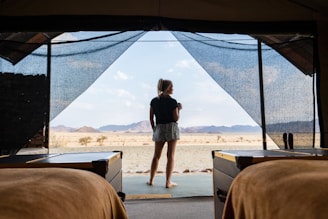 a woman standing in a tent looking out at the desert