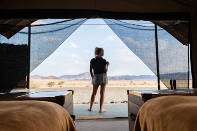 a woman standing in a tent looking out at the desert