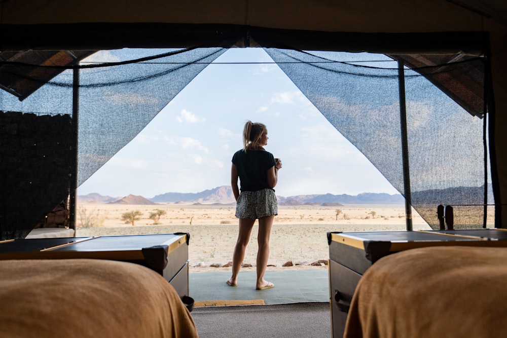 Une femme debout dans une tente regardant le désert