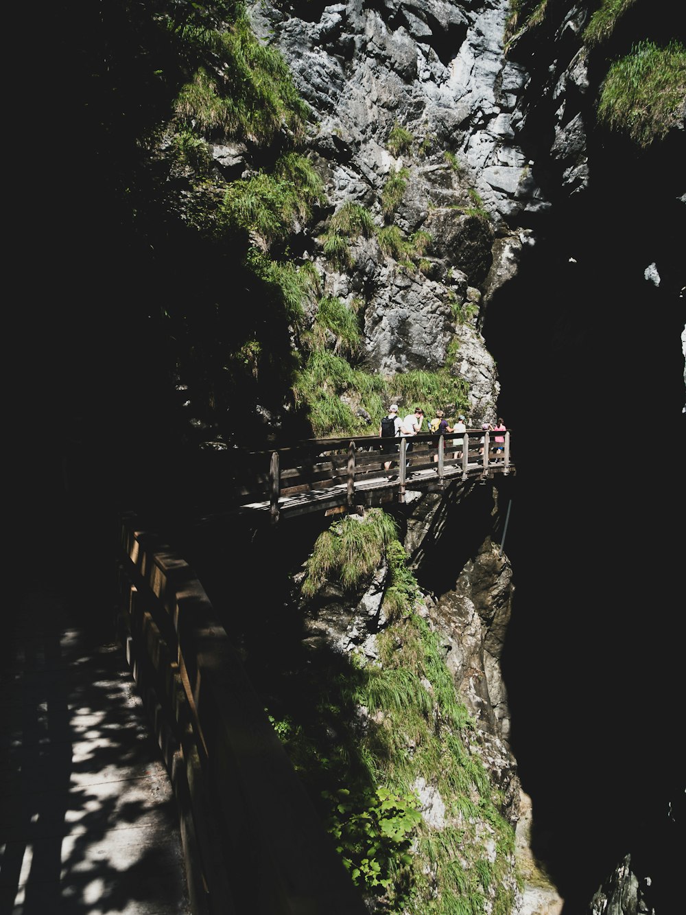 a group of people walking across a wooden bridge