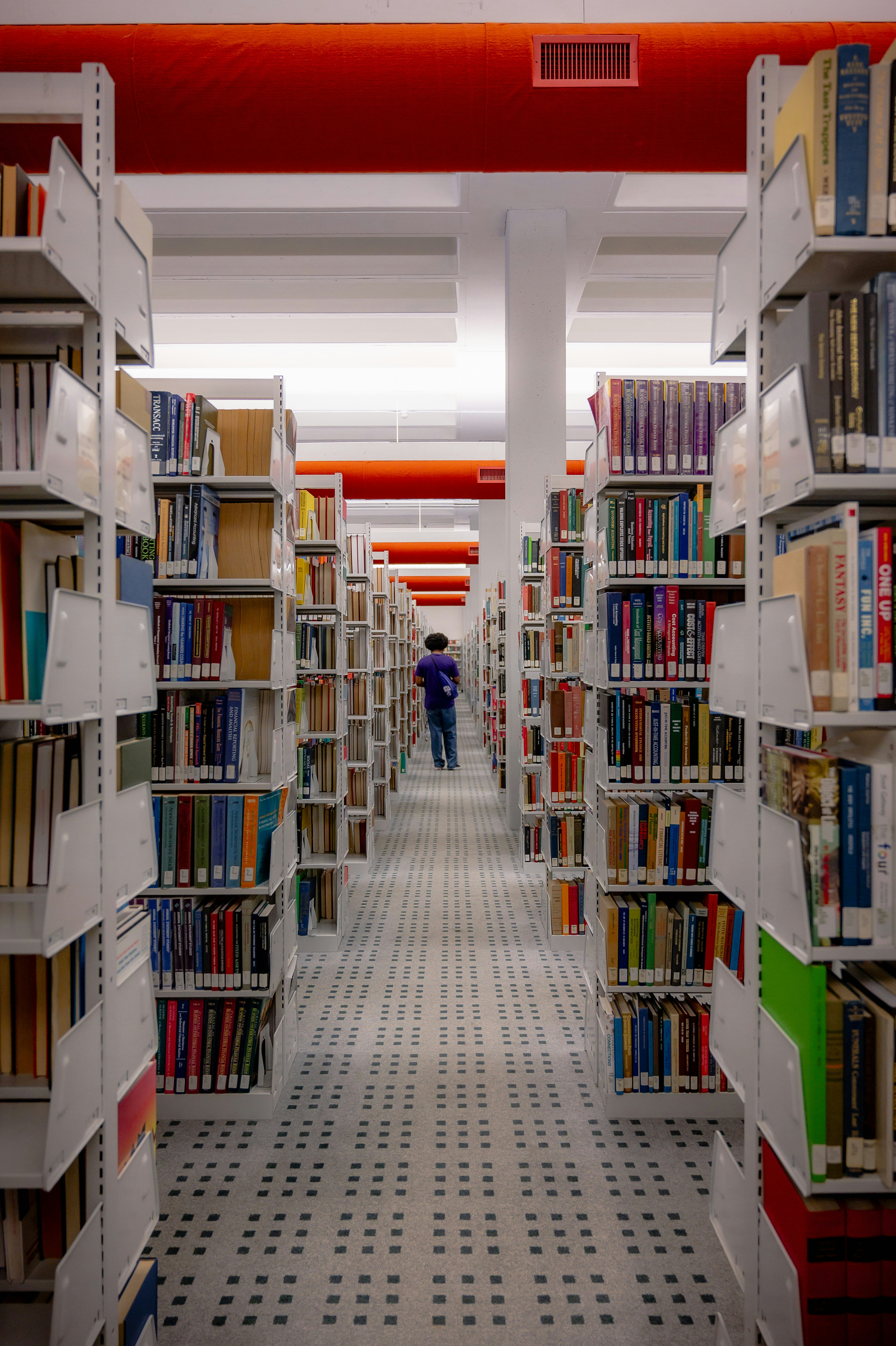 a man walking through a library filled with lots of books