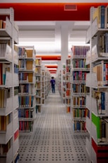a man walking through a library filled with lots of books