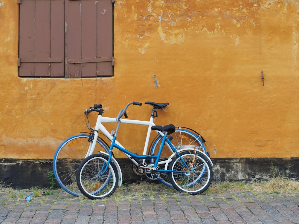 a blue and white bike leaning against a yellow wall