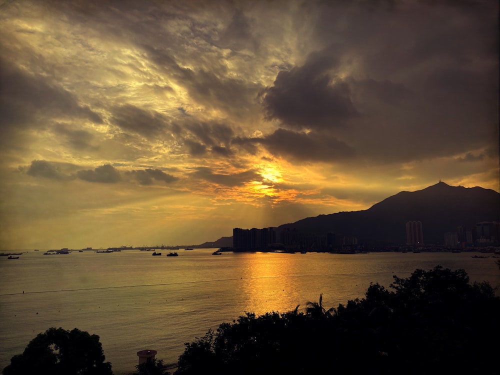 a sunset over a body of water with a mountain in the background