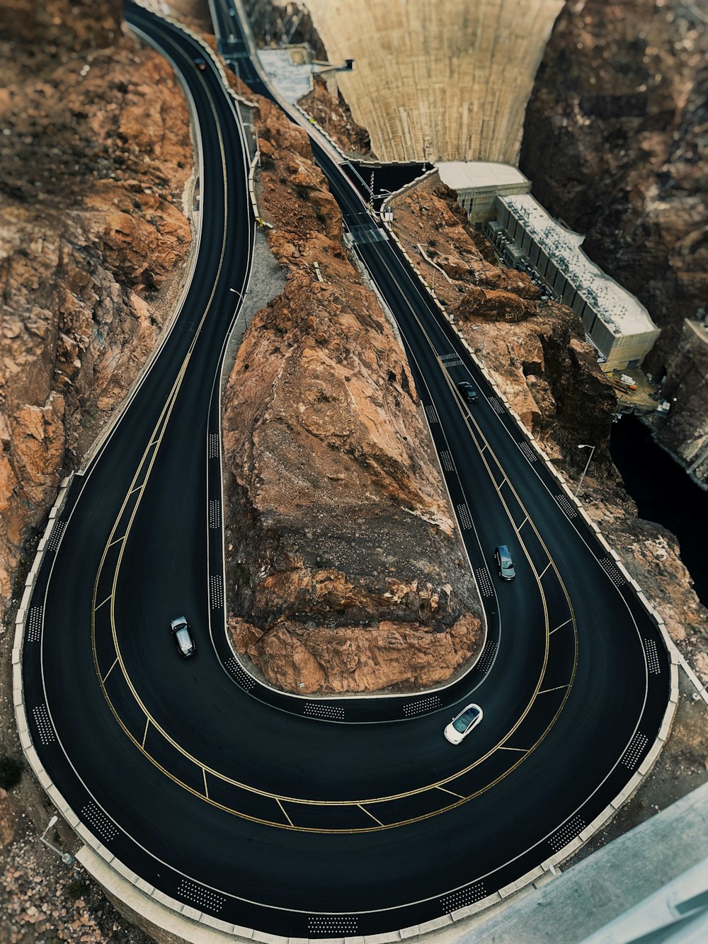 an aerial view of a winding road with a dam in the background