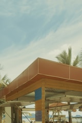 A cozy beach hut framed by palm trees with the sparkling ocean in the background at sunset.