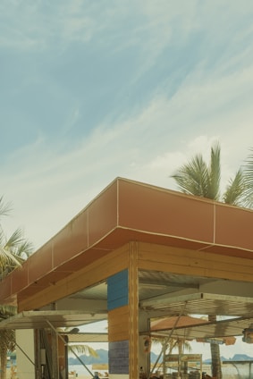 A cozy beach hut framed by palm trees with the sparkling ocean in the background at sunset.