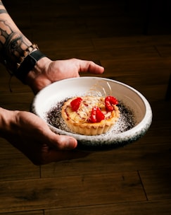 A confident baker presenting a beautifully plated dessert in a competition.