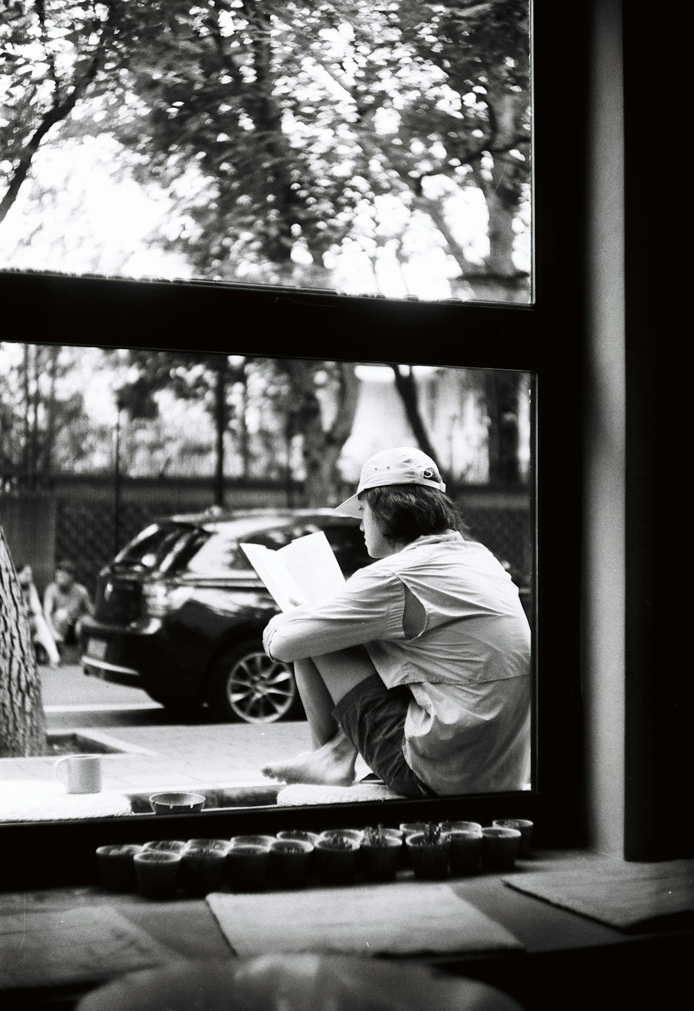 a man sitting on a window sill reading a book