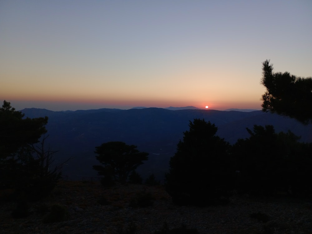 the sun is setting over a mountain range