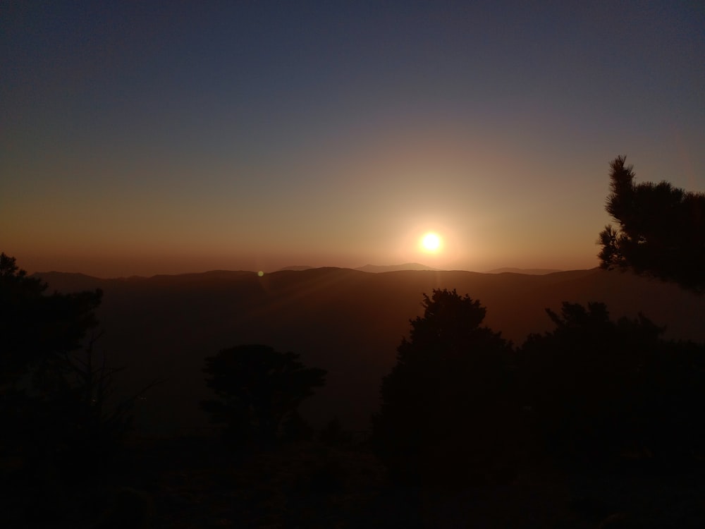 the sun is setting over a mountain range