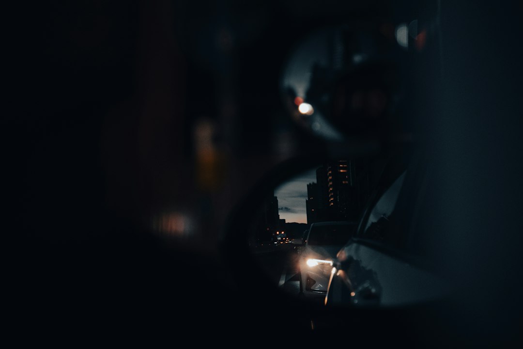 a car's side view mirror reflecting a city at night