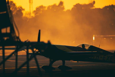 A small aircraft taxiing on a runway at sunrise with warm golden light.