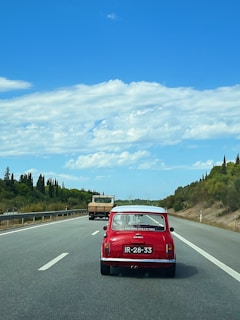 A stylish blue Mini 5 Door driving along a coastal road with ocean views.