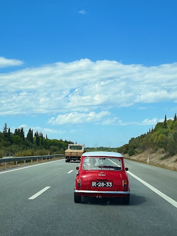 A stylish blue Mini 5 Door driving along a coastal road with ocean views.