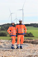 Engineers inspecting a wind turbine base with safety gear and tools