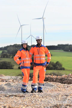 Engineers inspecting a wind turbine base with safety gear and tools