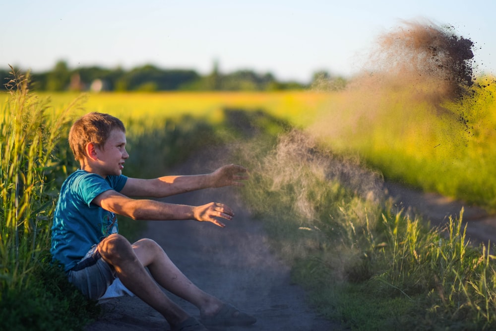 a man sitting on a dirt road in a field