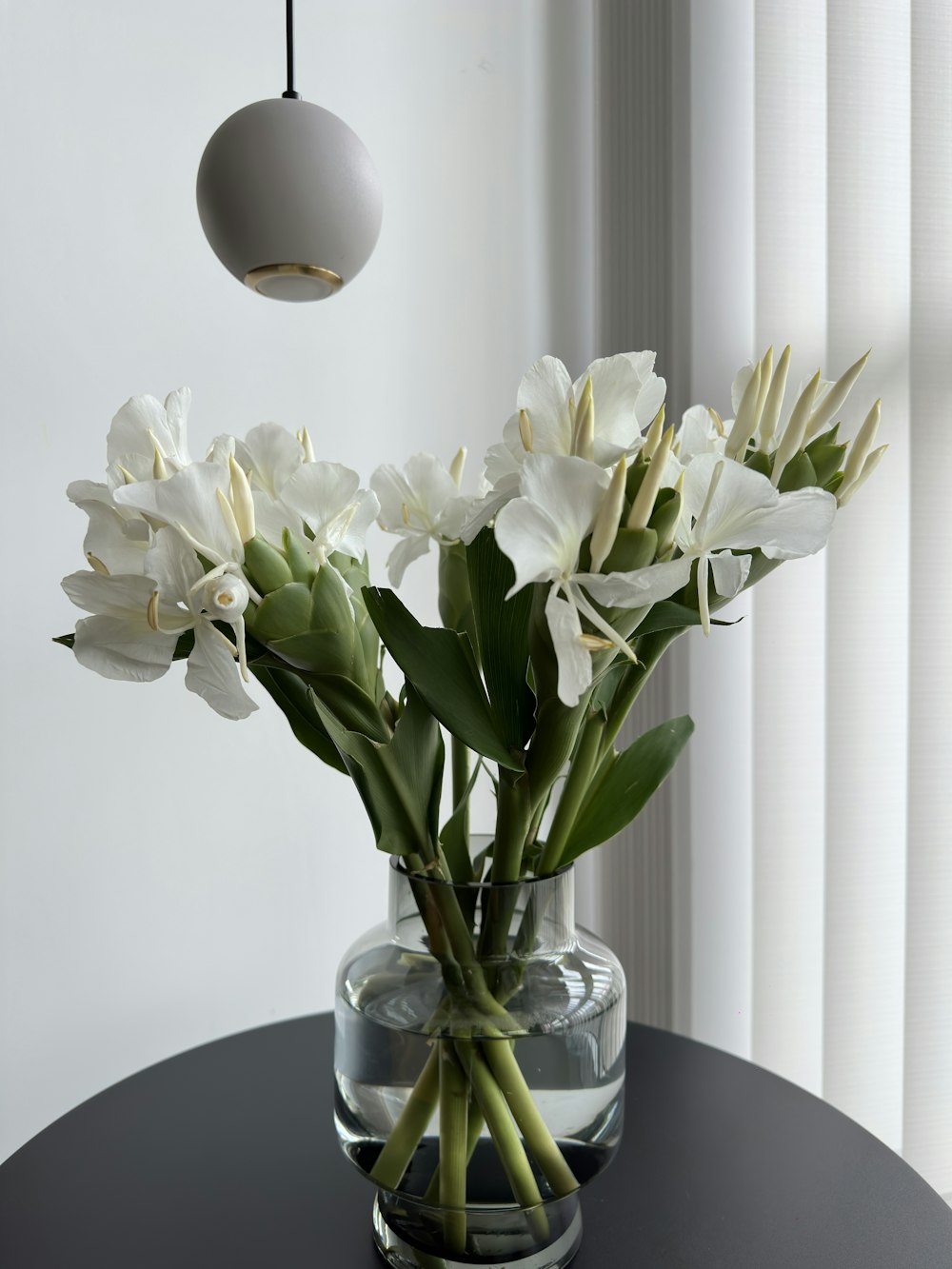 un vase avec des fleurs blanches assis sur une table