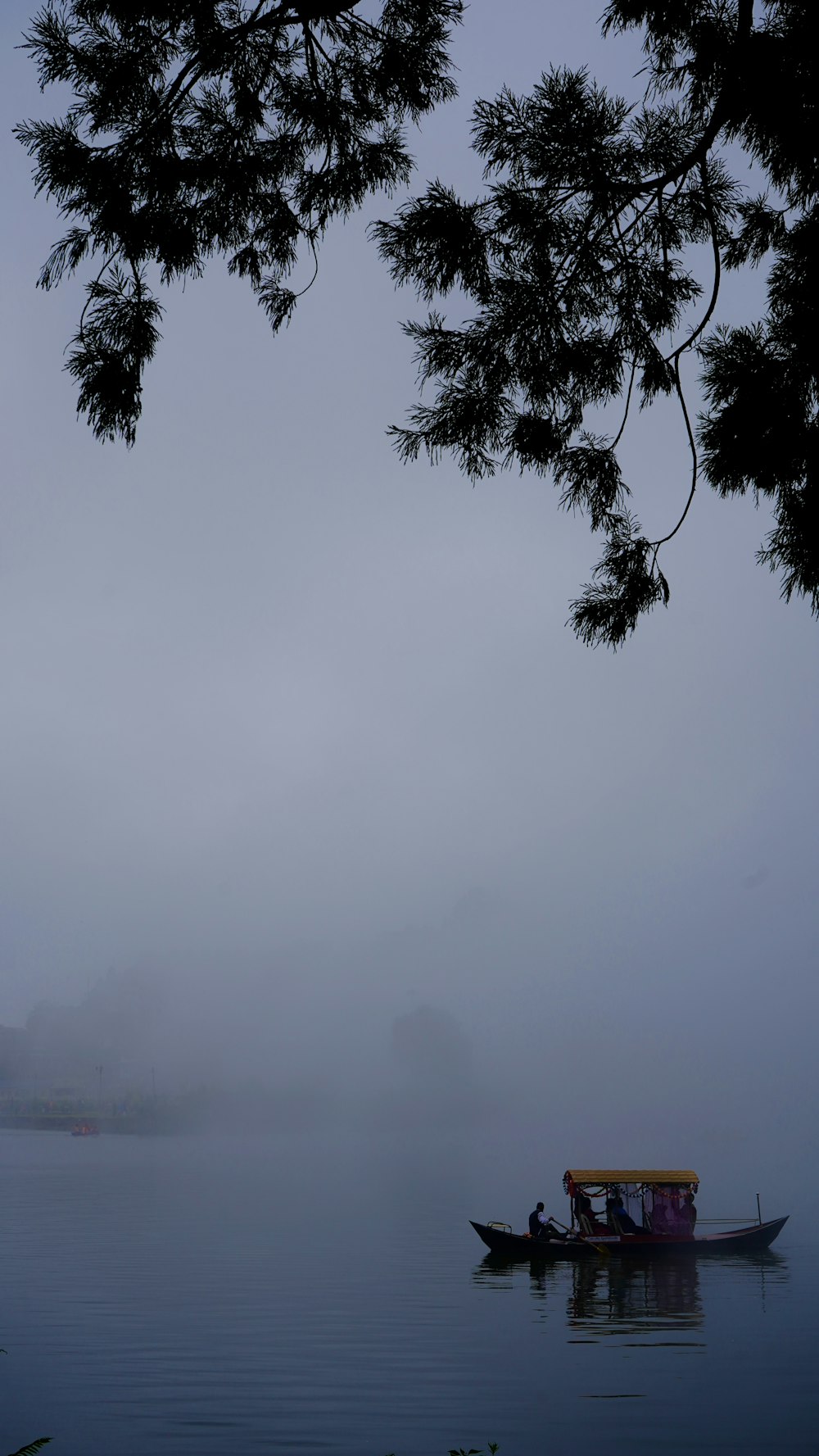 a small boat floating on top of a lake on a foggy day