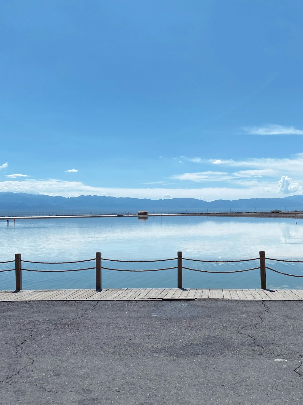 a bench sitting on the side of a pier next to a body of water