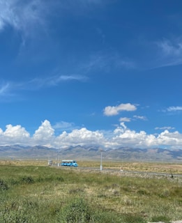 A scenic highway view with a bus traveling through green hills under a blue sky.