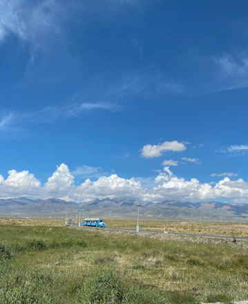 A scenic highway view with a sleek bus cruising past green fields under a clear blue sky.