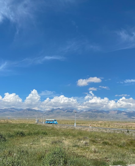 A spacious bus driving on a scenic road.
