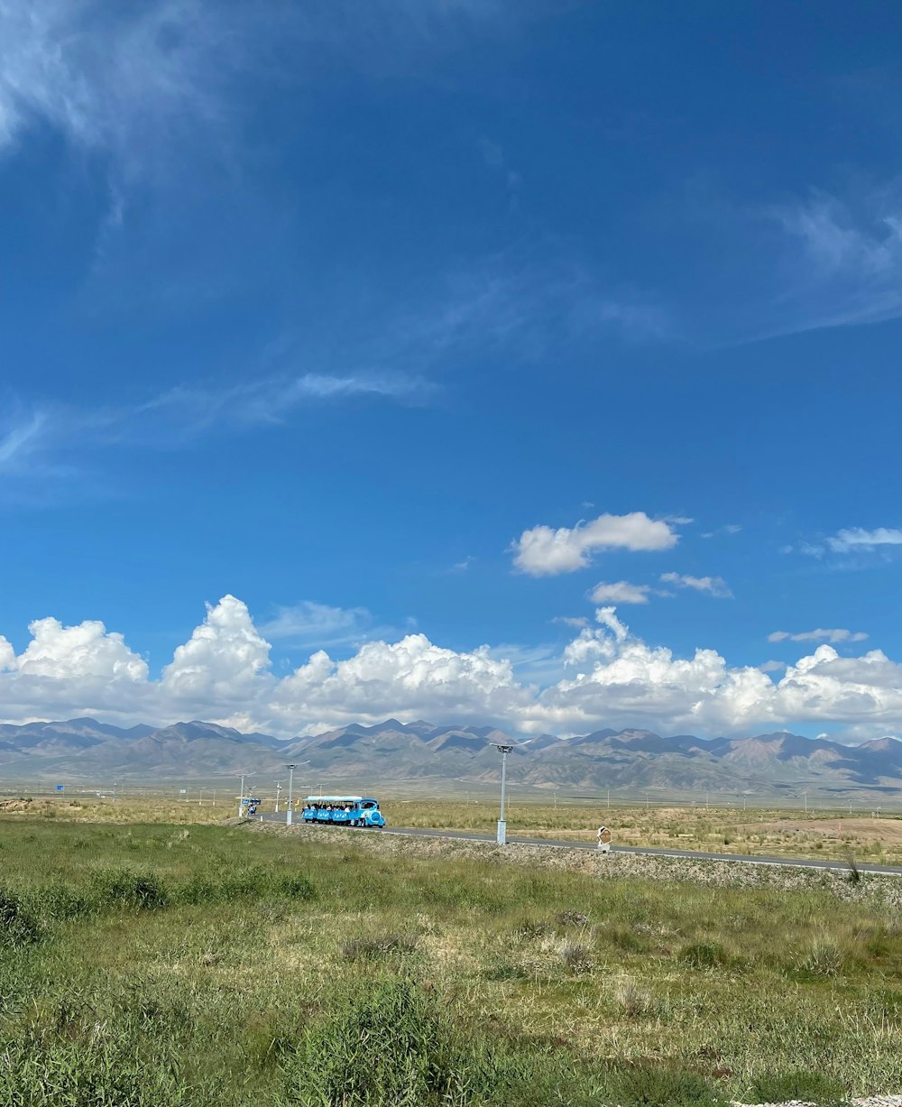 a blue train traveling through a lush green field