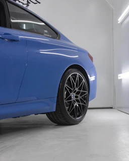 A sleek close-up of a luxury car's air suspension system glowing under subtle blue workshop lighting.