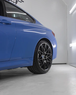A sleek close-up of a luxury car's air suspension system glowing under subtle blue workshop lighting.